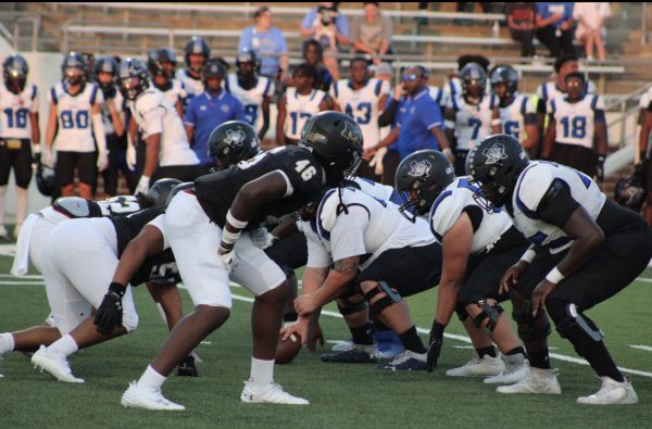 Varsity football players preparing to defend a play from Summit during the 2023-24 Blackout game.